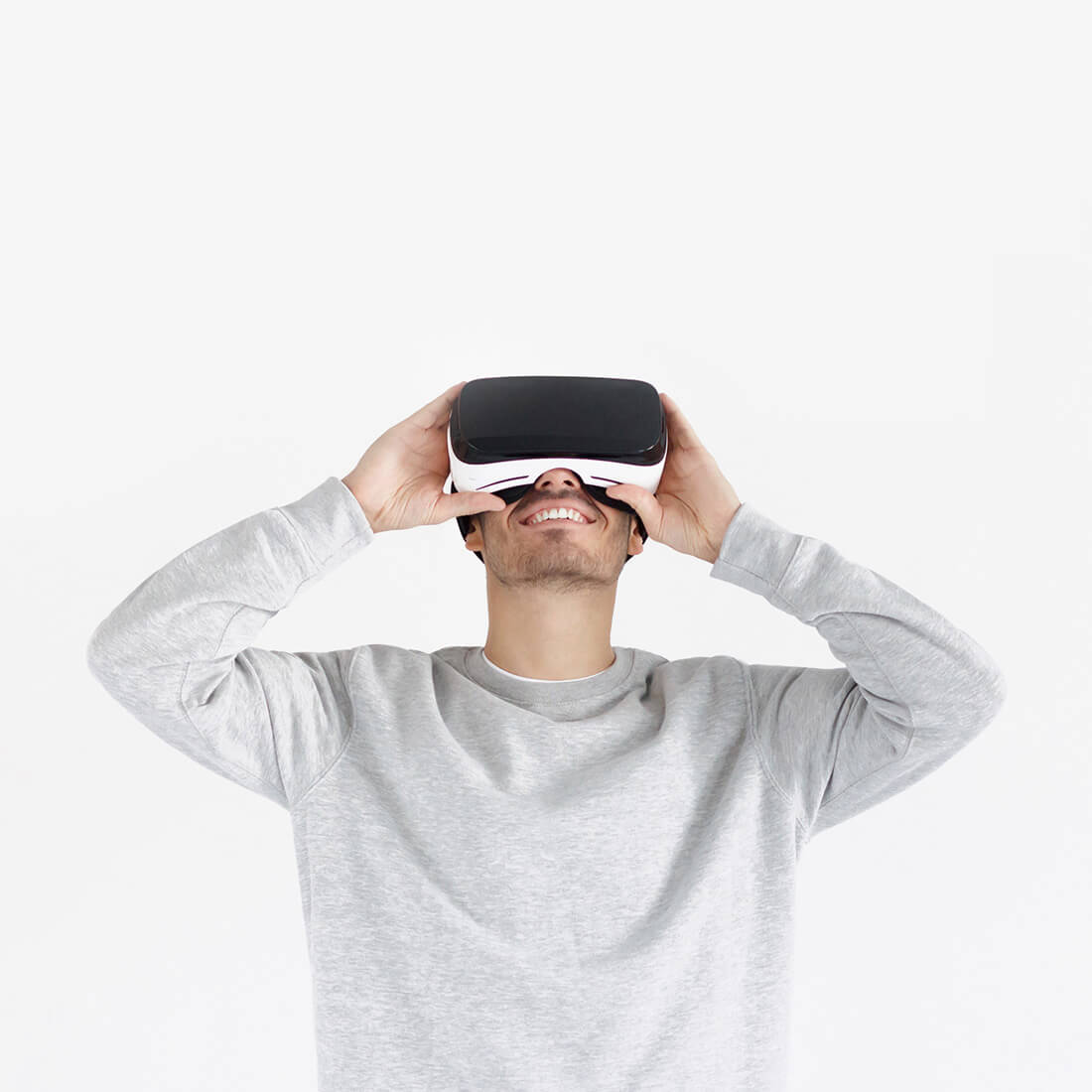 A man wearing a gray sweatshirt and holding a vr headset.