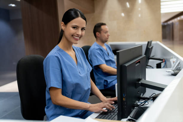 Two people in scrubs are sitting at a computer.